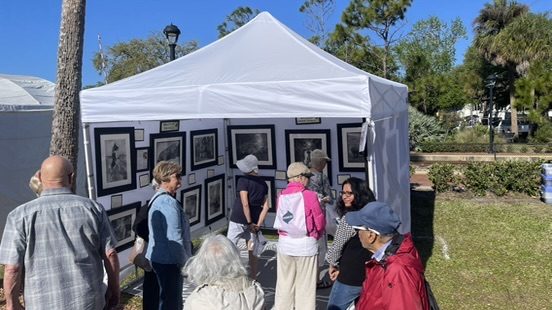 Visitors gathered outside a white festival tent viewing artwork